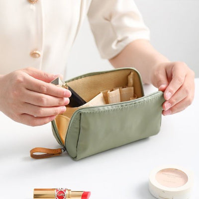 Femme range son maquillage dans trousse de toilette femme verte 